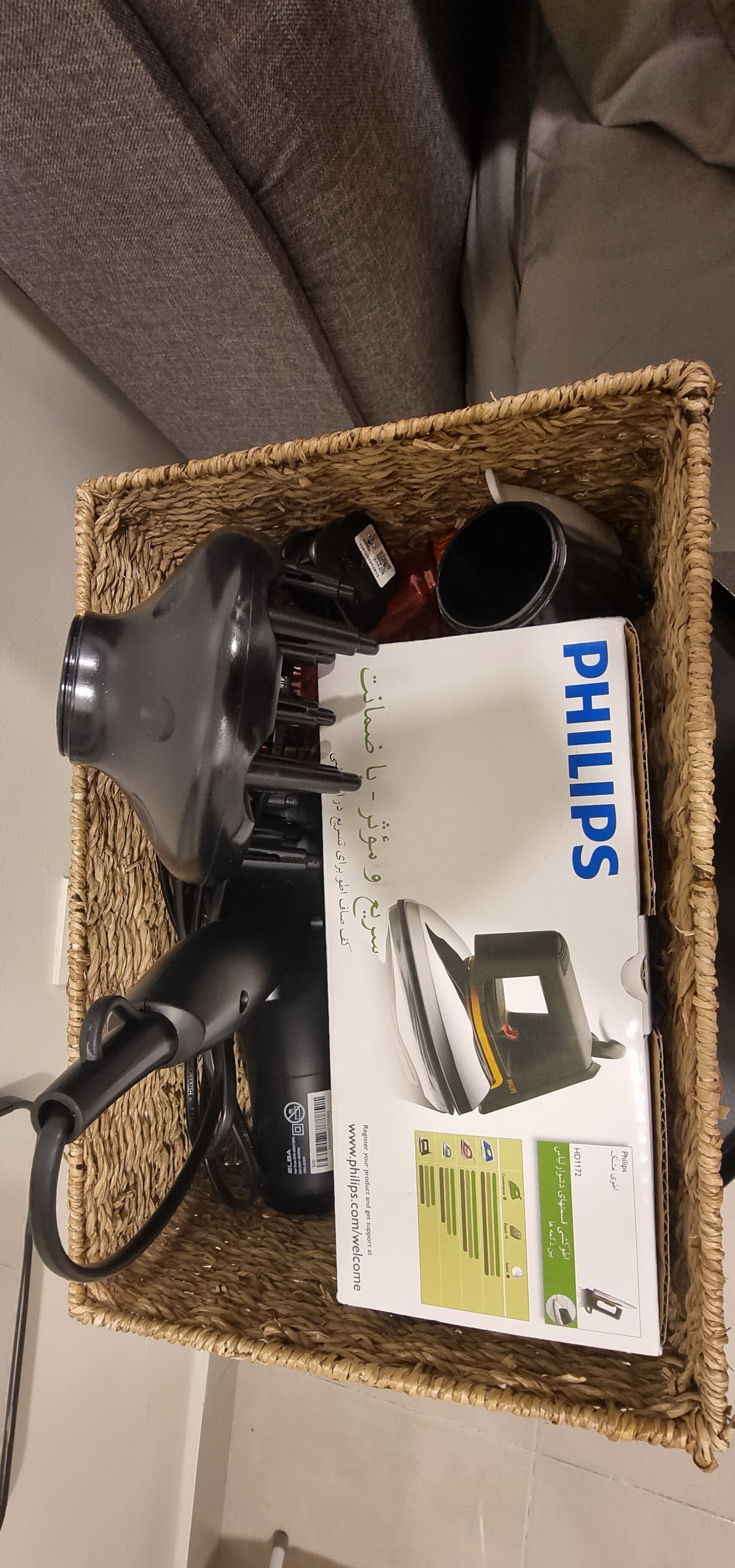 A Philips hair dryer and its box in a woven basket.