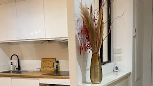 Una cucina moderna con mobili bianchi, un piano di lavoro in legno e un vaso con piante essiccate.