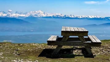Une table de pique-nique en bois, posée sur un terrain rocheux, d’où l’on peut admirer des montagnes enneigées au loin.