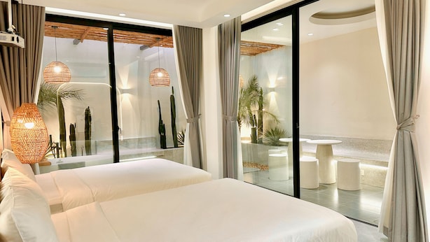 Une chambre d’hôtel moderne dotée d’un grand lit, d’un balcon avec un coin repas et offrant une vue sur l’extérieur.