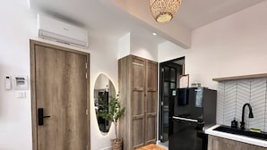 Une cuisine moderne avec une porte en bois, un climatiseur, un réfrigérateur noir et un évier avec un robinet noir.