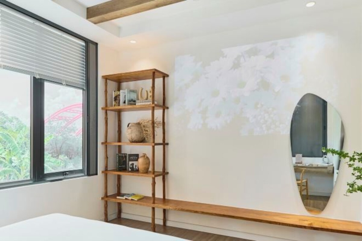 Une pièce avec une bibliothèque en bois, un grand miroir et un mur blanc orné d’un motif texturé.