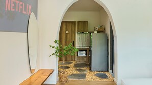 Une cuisine moderne avec un sol en pierre, des meubles en bois, un réfrigérateur et une petite plante en pot.