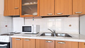 A kitchen with wooden cabinets, a microwave, a sink, and a stove. - Nice apartment on the first floor with a covered balcony (Baska)