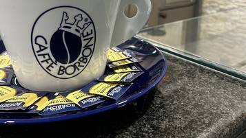 Una tassa de cafè blanca amb un logotip sobre un safata blava, damunt d'un taulell de granit.