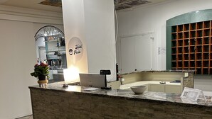 A hotel reception desk with a stone counter, a laptop, and a potted plant. - Hotel Perla (Cesenatico)
