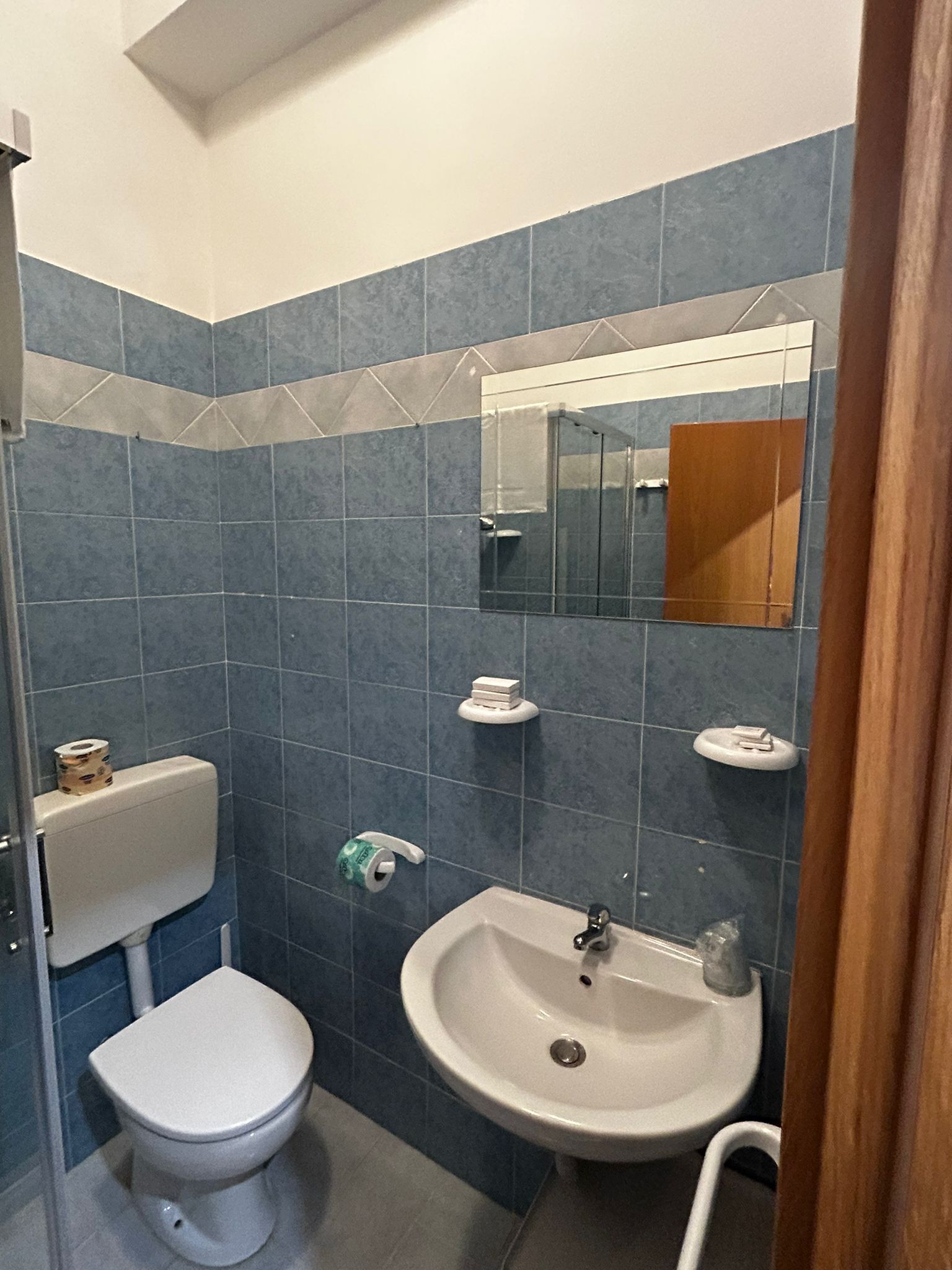 A bathroom with a toilet, sink, and mirror.