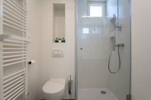 Bathroom features a toilet, shower with handheld showerhead, and towel rack.