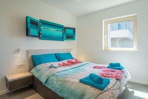 Relax in a serene bedroom with a large bed, nightstand, and artwork above, offering a peaceful retreat.