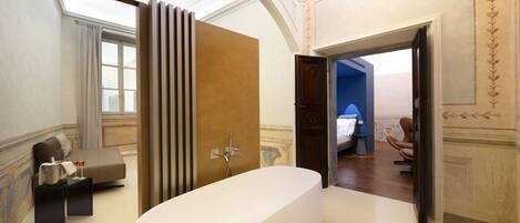 A modern bathroom with a freestanding bathtub, a vanity with a mirror, and a window with curtains.