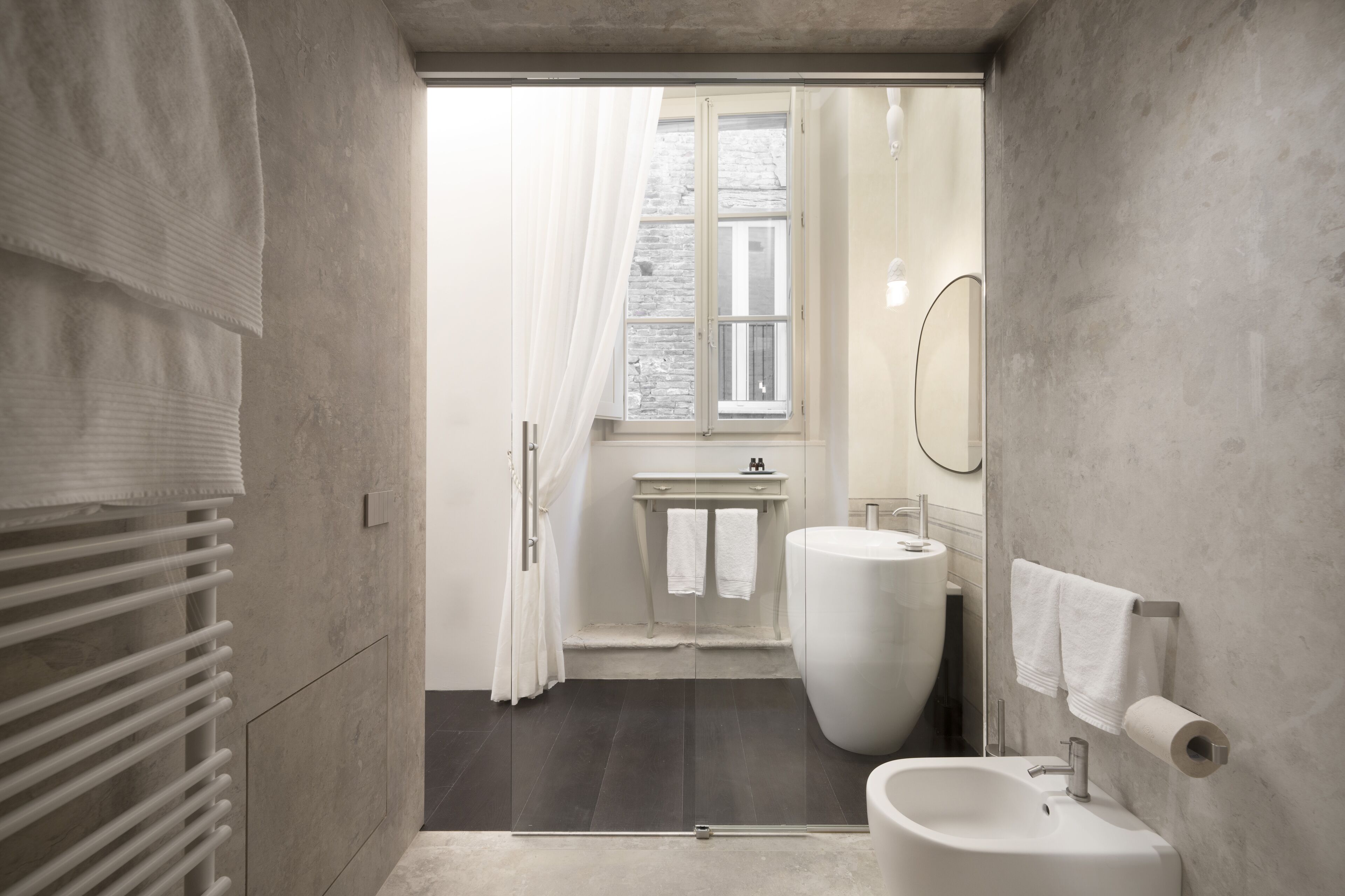 A modern bathroom with a large bathtub, a sink, and a window with curtains.