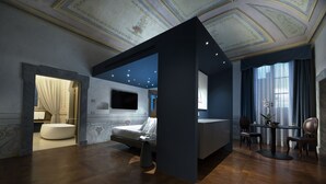 A modern hotel room with a large bed, a seating area, and a dining table. - Palazzo Giusti Suites and Spa (Urbino)