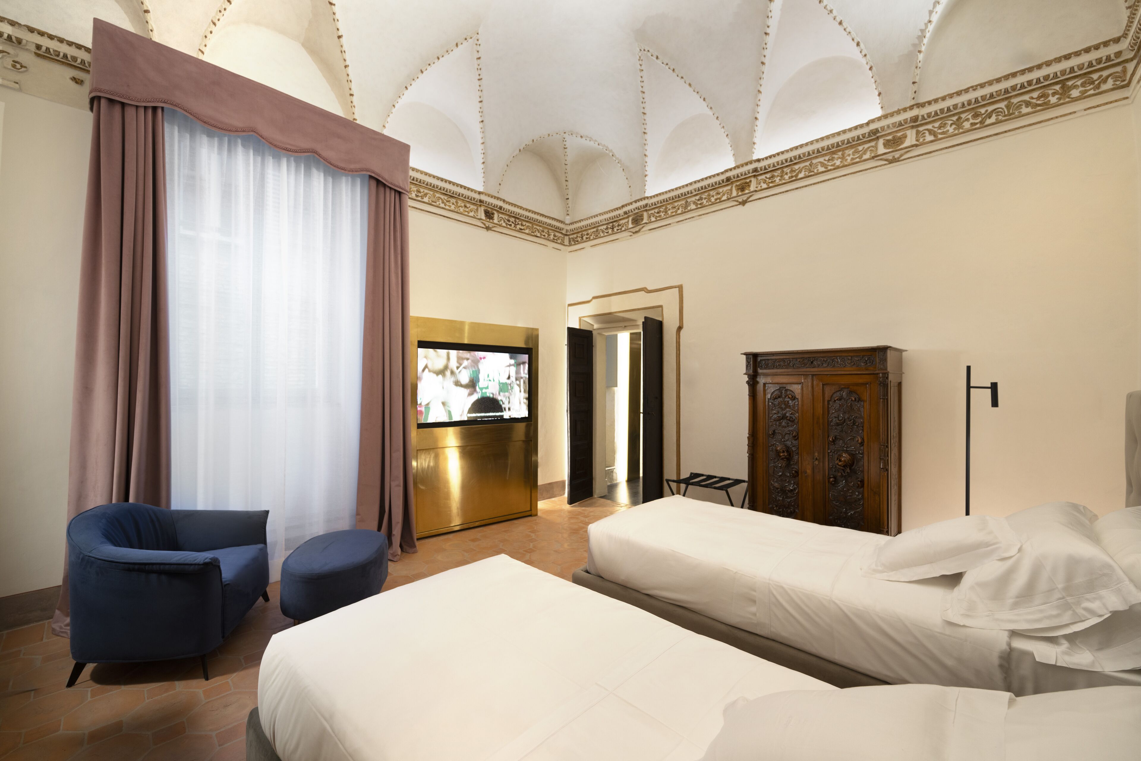 Una habitación de hotel con dos camas, televisión, escritorio y armario.