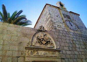 Standing tall, this historic clock tower showcases traditional design with clock faces on each side, complemented by a stone relief with intricate carvings.