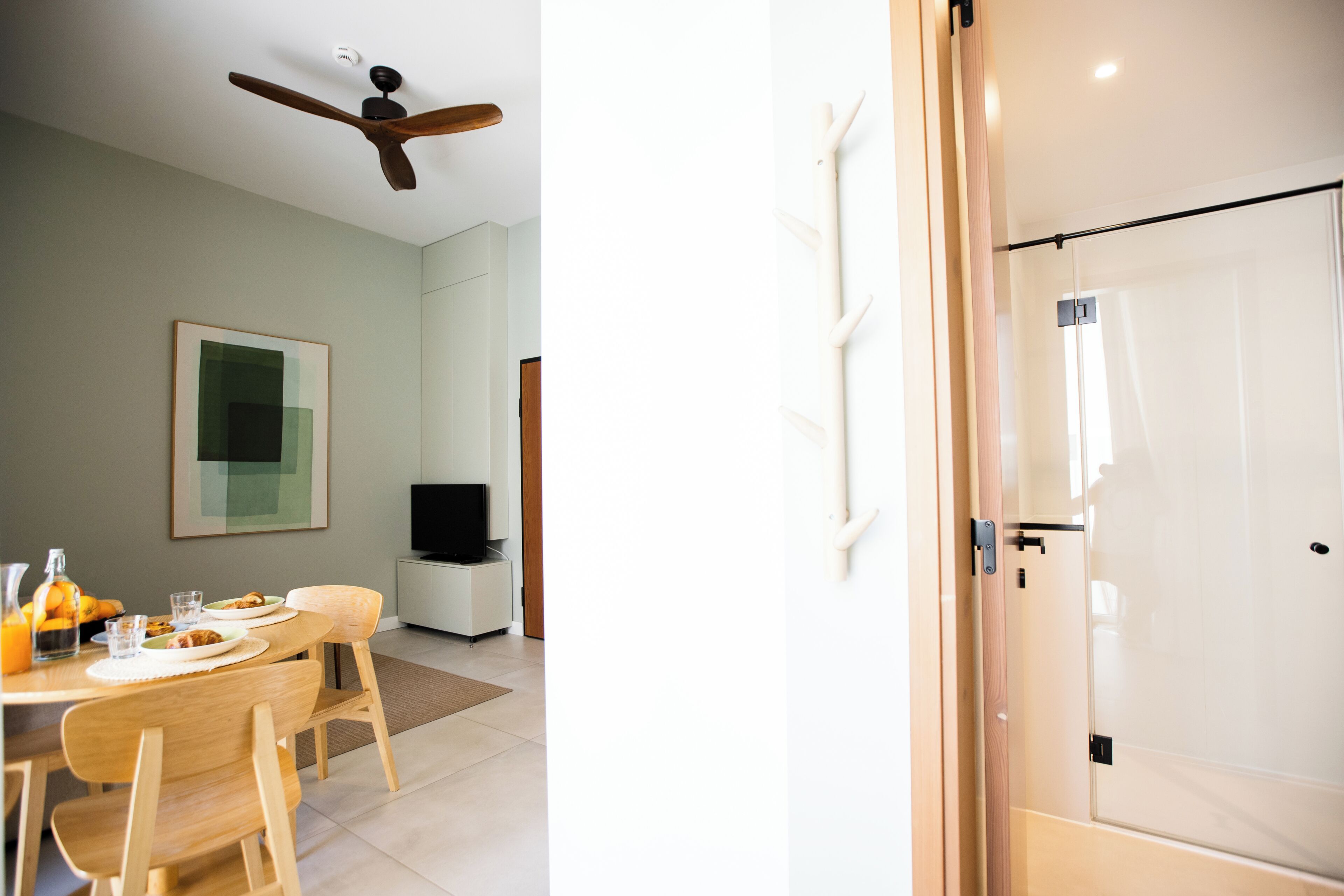 A modern kitchen with a dining area, a ceiling fan, and a television.