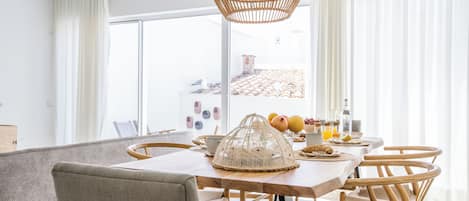 Un comedor moderno con una mesa de madera, sillas de mimbre y una lámpara colgante.