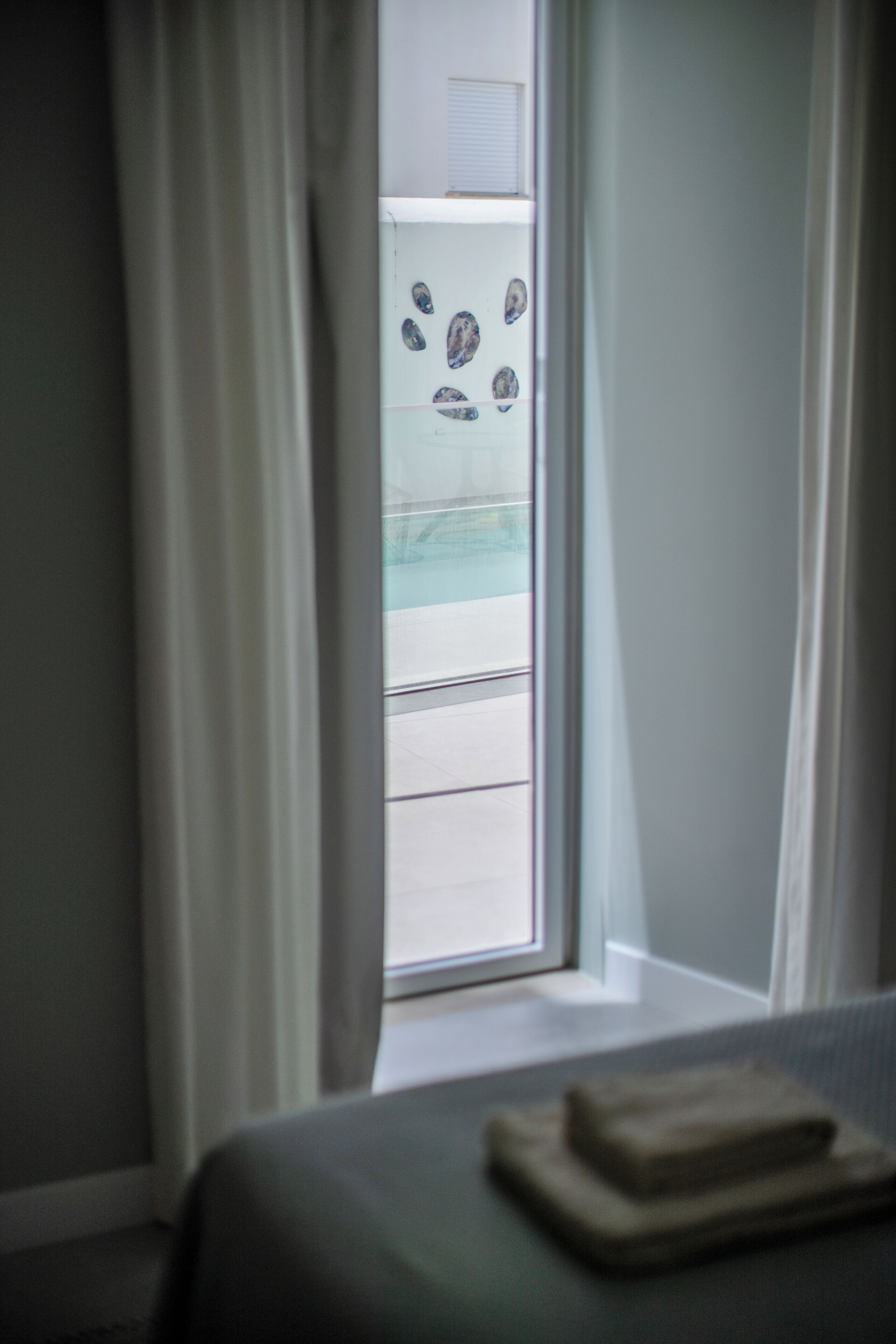 A room with a bed, a window with curtains, and a view of a pool outside.