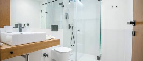 A modern bathroom with a glass-enclosed shower, a white sink, and a toilet.
