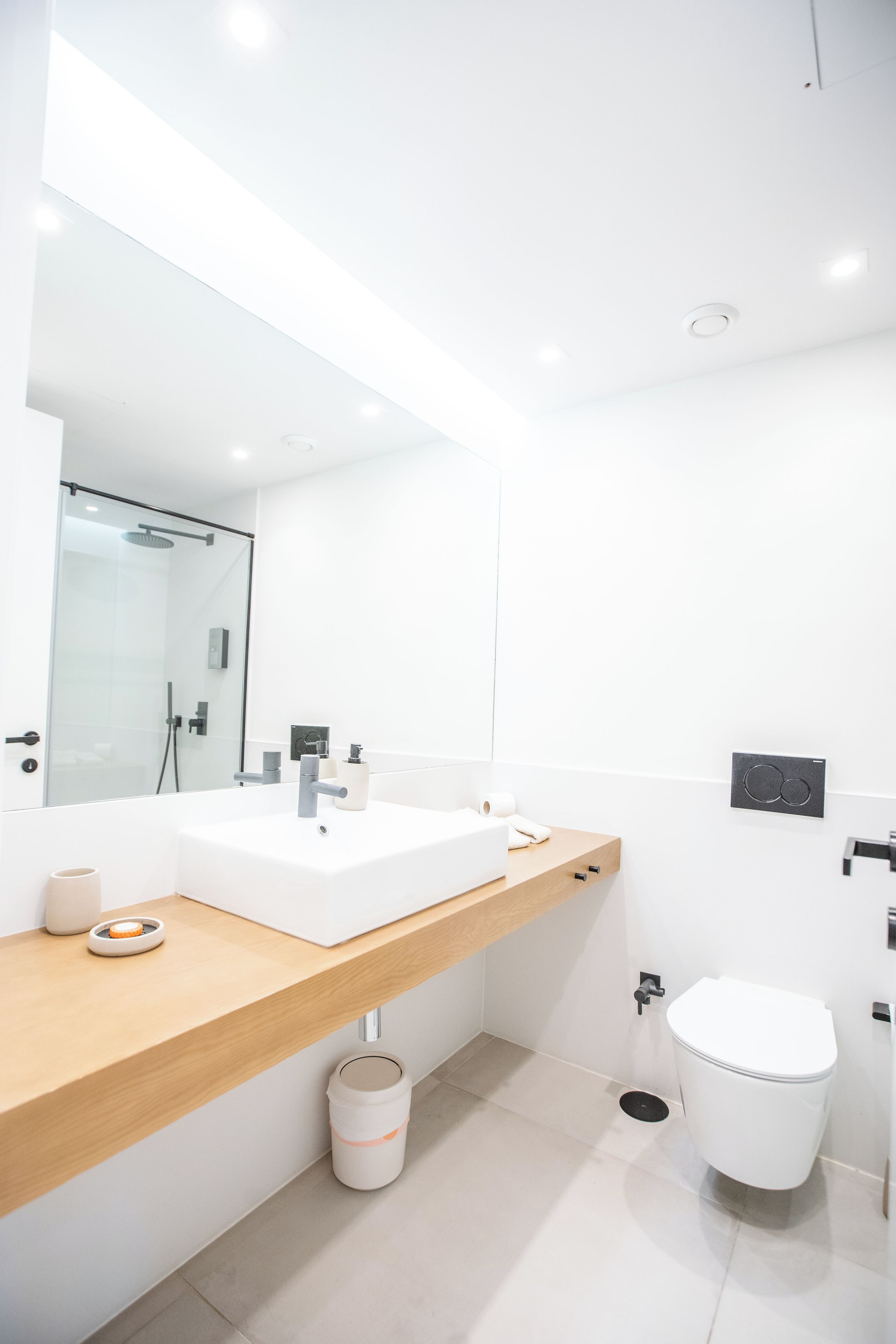 A modern bathroom with a white sink, a mirror, and a toilet.