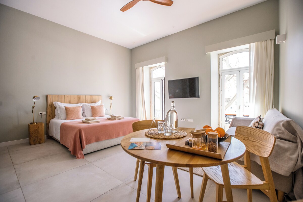 Un dormitorio con cama, mesita de noche y un comedor con mesa y sillas.
