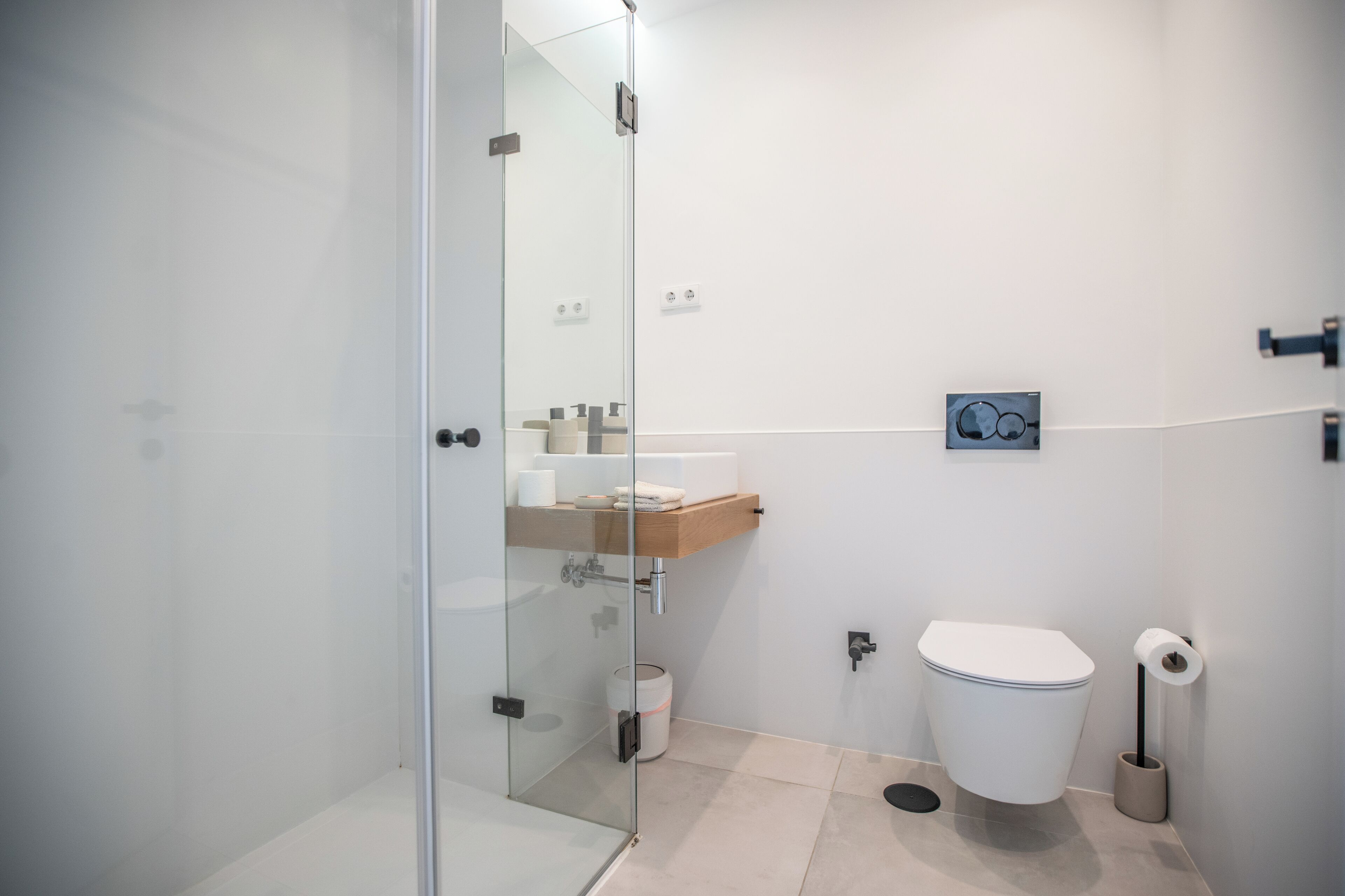 A modern bathroom with a glass shower enclosure, a toilet, and a sink with a mirror above it.