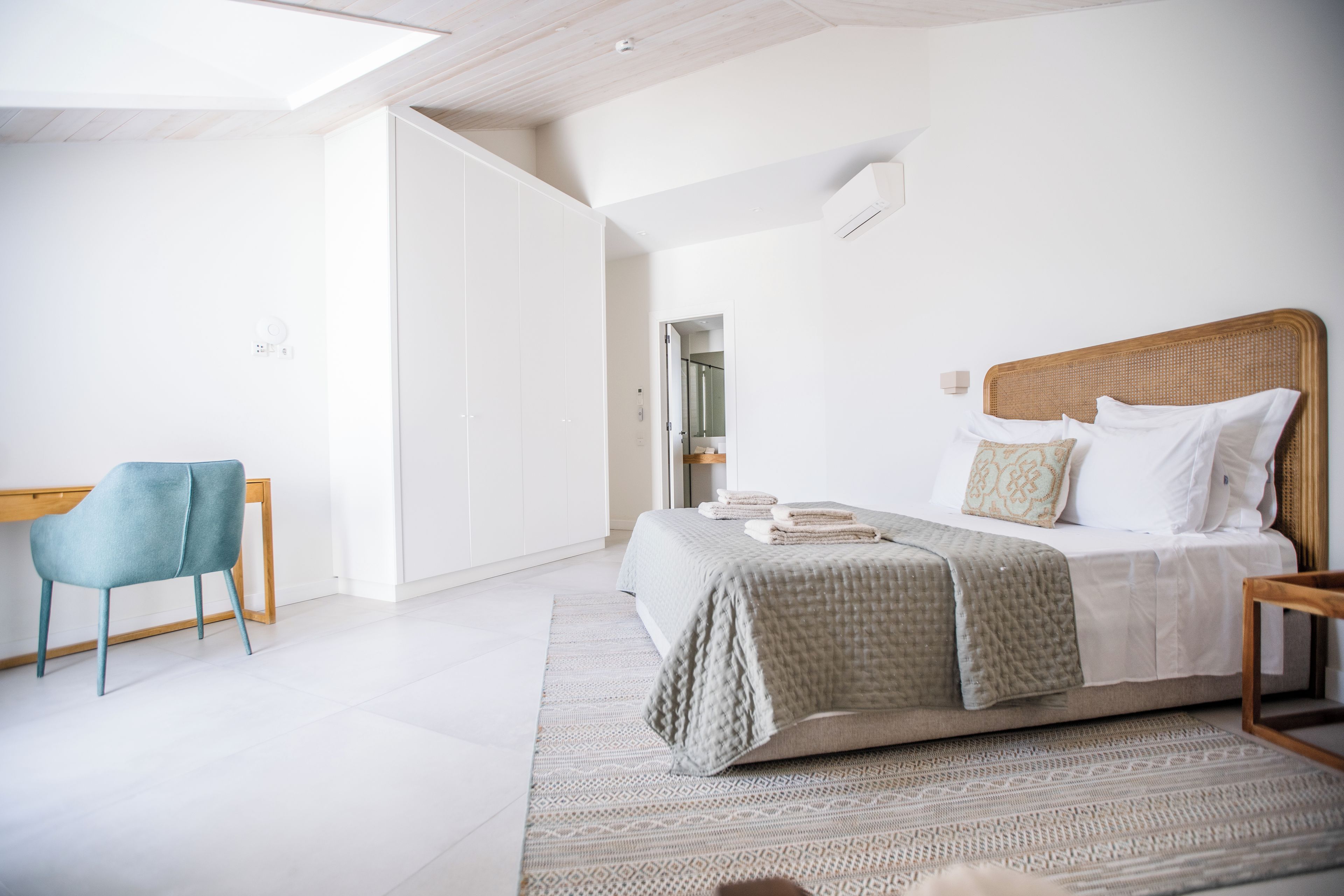 Een moderne slaapkamer met een groot bed, een fauteuil en een inloopkast.