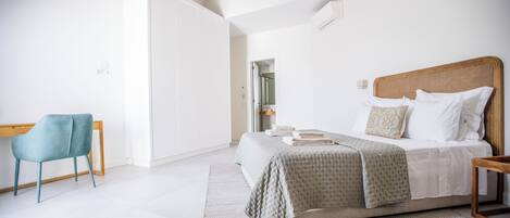 Een moderne slaapkamer met een groot bed, een fauteuil en een inloopkast.