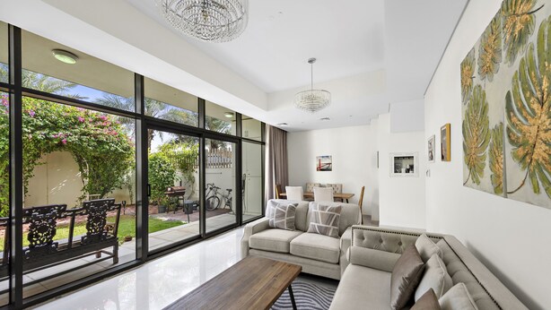 A spacious living room with a large window, a sofa, a coffee table, and a chandelier.
