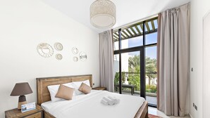 A hotel room with a large bed, a nightstand with a lamp, a calendar, and a view of the outdoors through a large window.