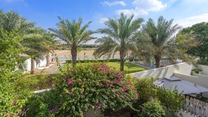 A view of a landscaped area with palm trees and a building with a white facade.