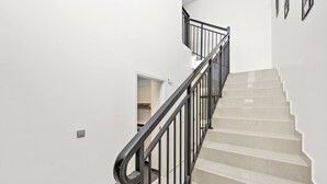 A staircase with black railings and beige steps leading to an upper floor.