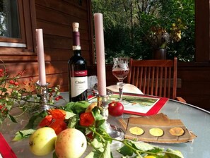 A table set with a bottle of Chianti wine, a glass of red wine, fresh fruits, and a book. - Romantisches Blockhaus an der Märchenstraße! (Reinhardshagen)