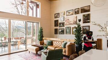 A cozy living room with a leather sofa, a dining table, and a bear statue.