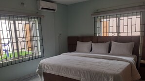 A bedroom with a bed, a headboard, and barred windows. - Biddex Lodge - by Cenlotts (Benin City)