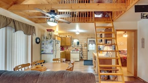 Interior acolhedor de uma cabana com área de jantar, cozinha e um quarto no mezanino.