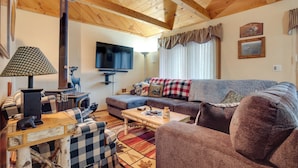 Uma sala de estar aconchegante com teto de madeira, televisão, sofá e mesa de centro.