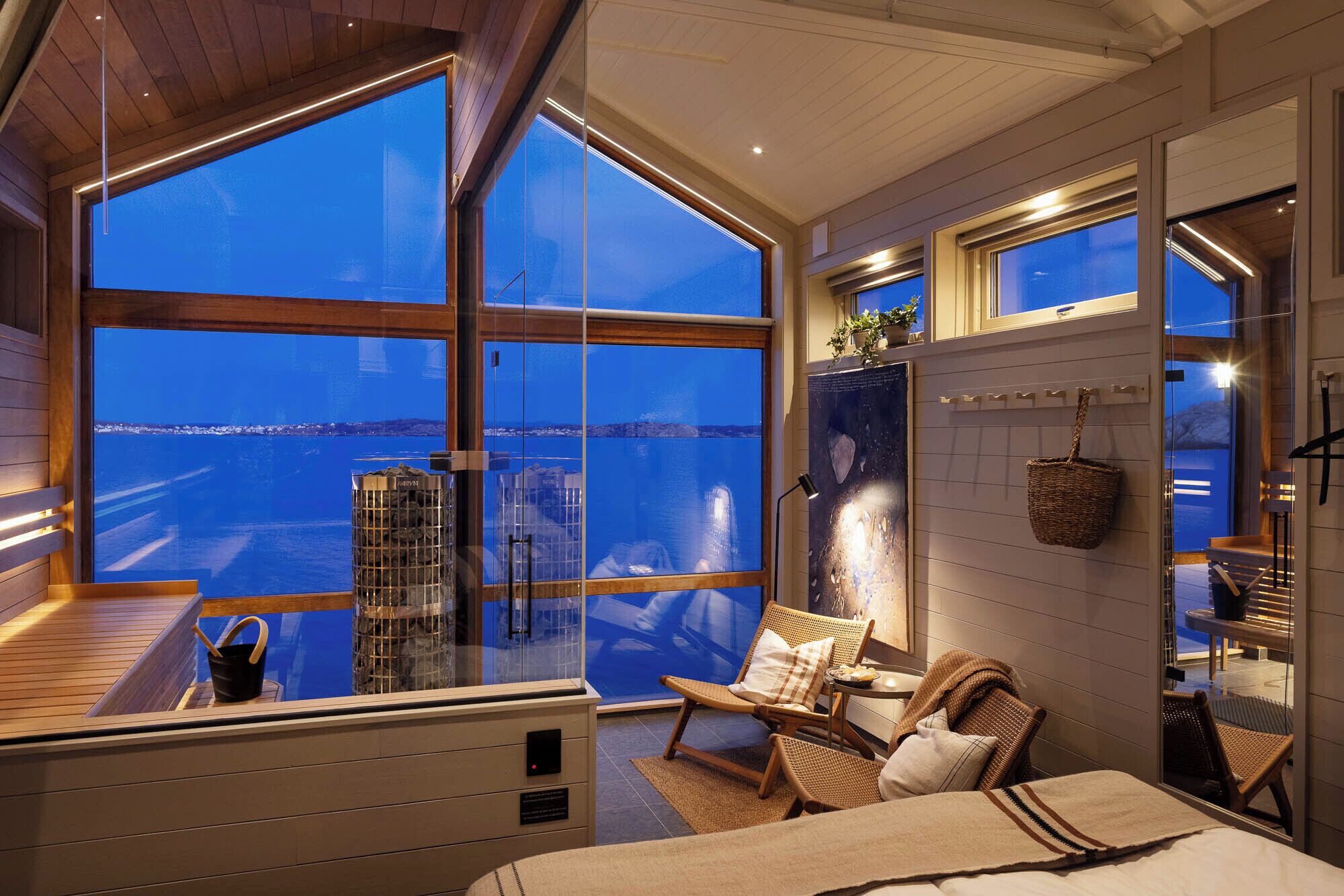 Una habitación con ventanas amplias, una cama, una silla y una mesita.