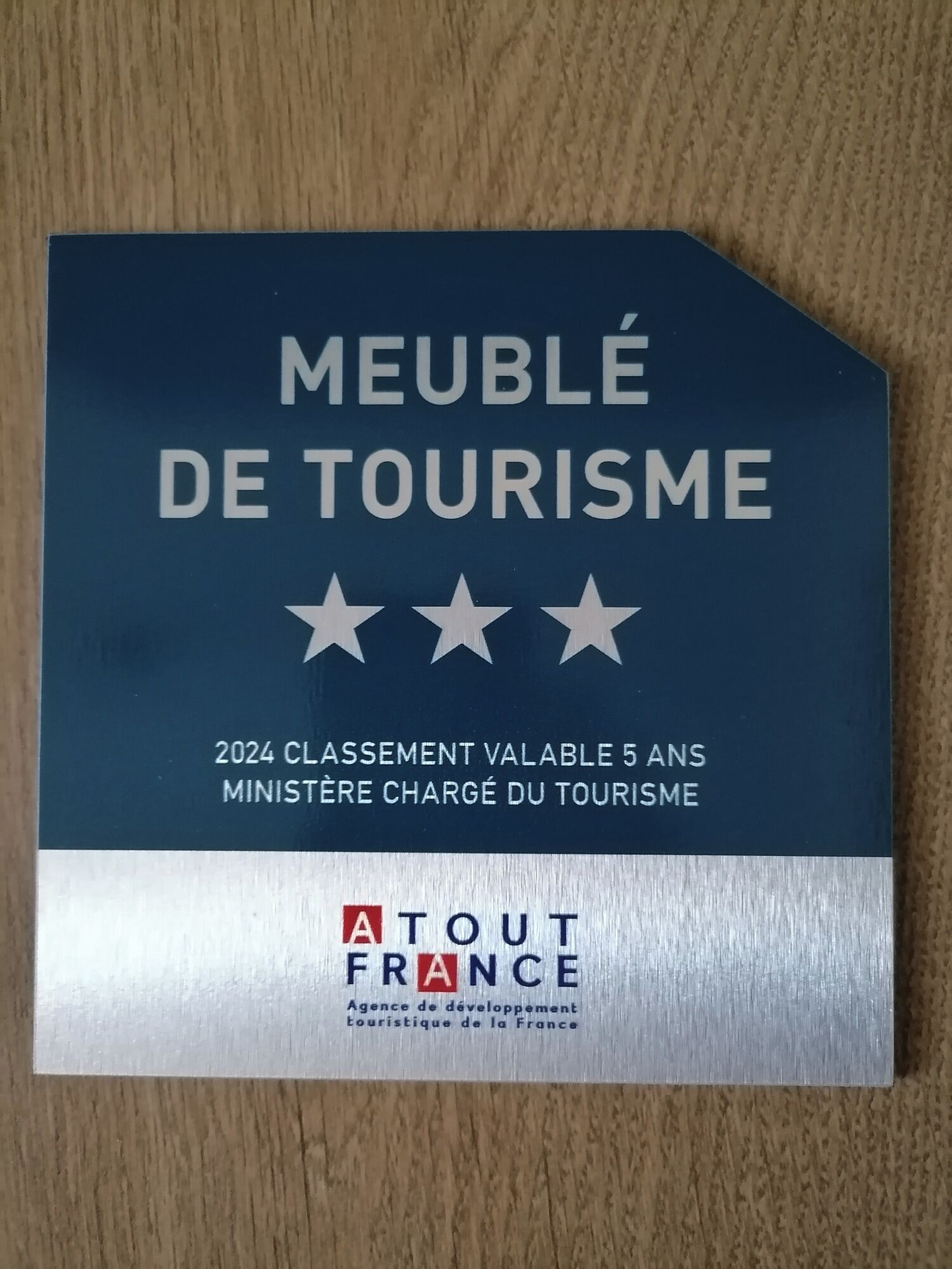 A blue award plaque for "Meublé de Tourisme" with a 2024 classifiable 5-year award from the French Tourism Agency.