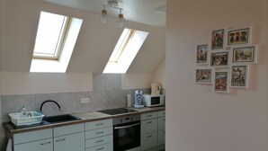 Una cocina moderna con tragaluces, microondas, hervidor y pileta.