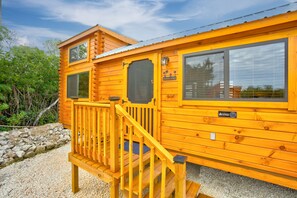 A wooden cabin with a deck, large windows, and a sign that reads "Pinecone."