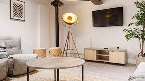 A modern living room with a round coffee table, a sofa, a floor lamp, a TV, and a minimalist wooden cabinet.