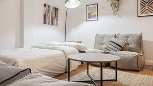 A modern, well-lit bedroom with a bed, a sofa, a small round table, and a decorative skull on the wall.