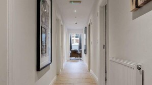A hallway with wooden flooring, white walls, and framed pictures. - Host & Stay | Slater Street Apartment IV (Liverpool)