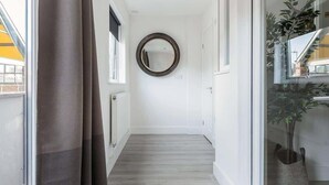 Ein Flur mit Holzboden, einem runden Spiegel an der Wand und einer Topfpflanze rechts.