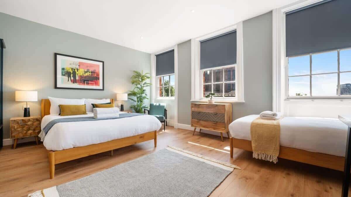 Habitación de hotel moderna con una cama grande, una cama más pequeña, un tocador y una ventana con vistas.