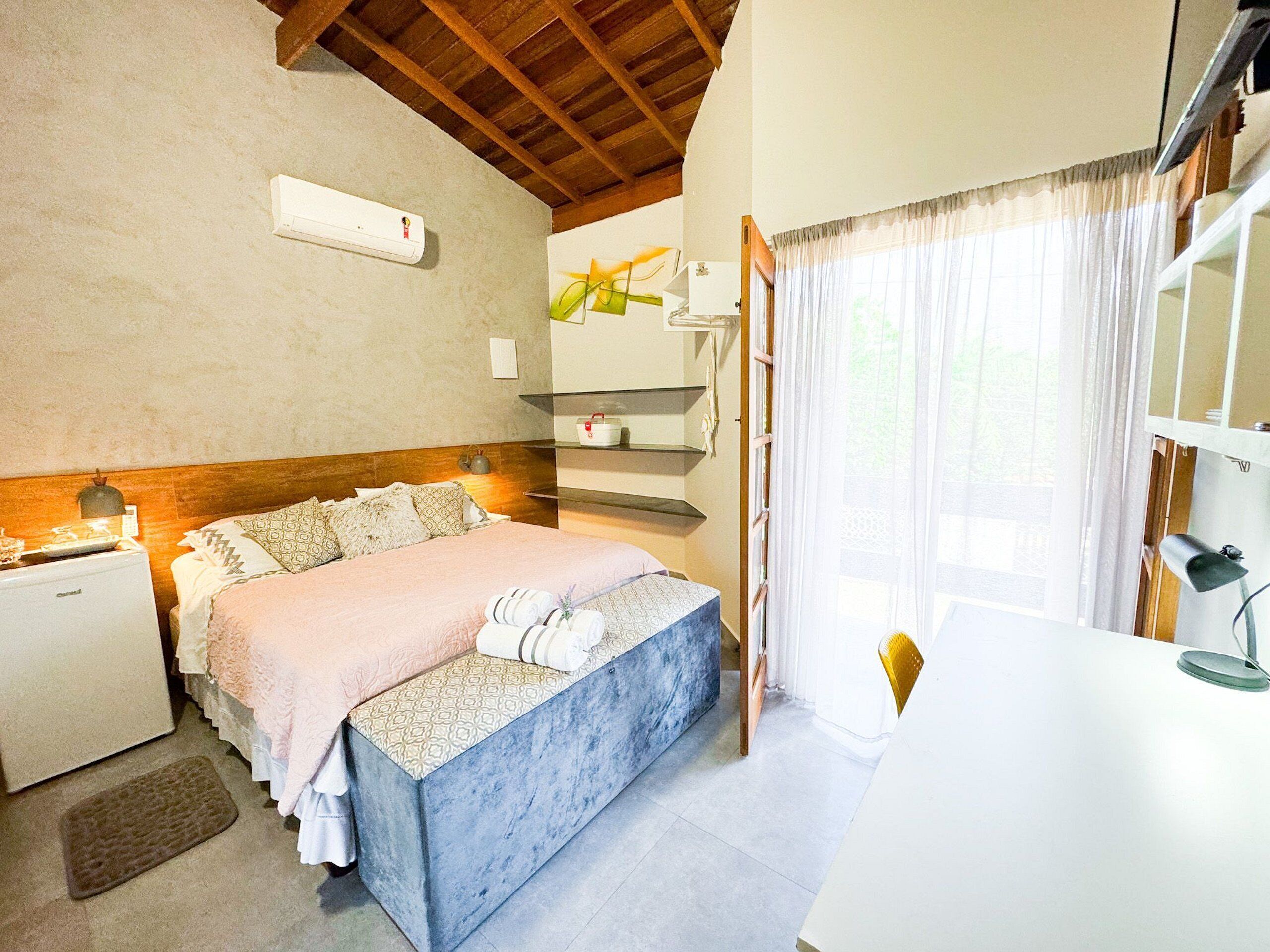 Ein Schlafzimmer mit einem Bett, Nachttischen, einem Schreibtisch und einem Fenster mit Vorhängen.