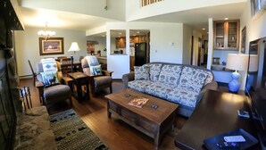 A spacious living room with a sofa, coffee table, and dining area. A kitchen is visible in the background. - Stunning Mountain Views! Fully Updated ! 2 miles from Purgatory Ski Resort (Durango)