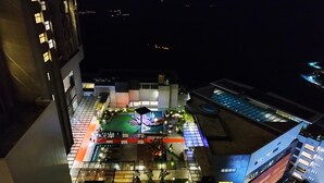 Vista aérea de un jardín en la azotea con zonas de estar y una piscina, rodeado de edificios modernos.