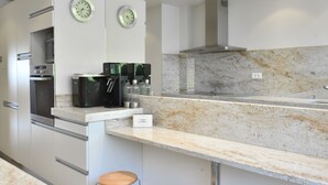 Une cuisine moderne dotée d’appareils électroménagers en acier inoxydable, d’un plan de travail en marbre et de deux tabourets.