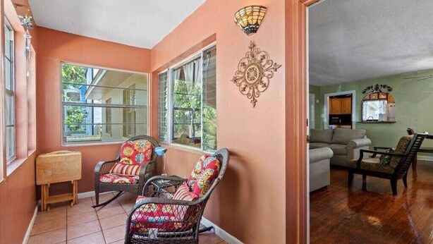 A sunroom with wicker chairs, a sofa, and a decorative wall lamp. - Lincolnville Cottage | Sunroom & Fenced Yard (St. Augustine)